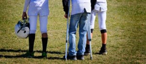 Injured football player on sidlines of game with crutches by team